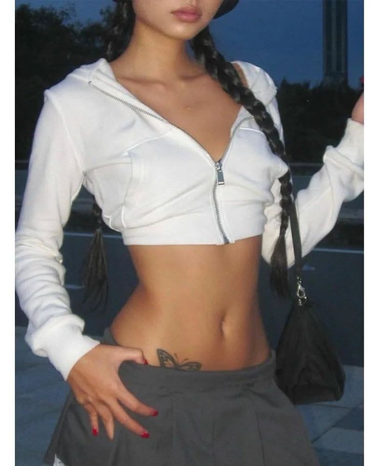 Woman in a white crop top with long braids and a butterfly tattoo
