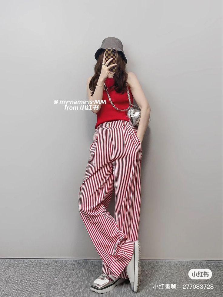 Person in a red tank top and striped pants taking a mirror selfie