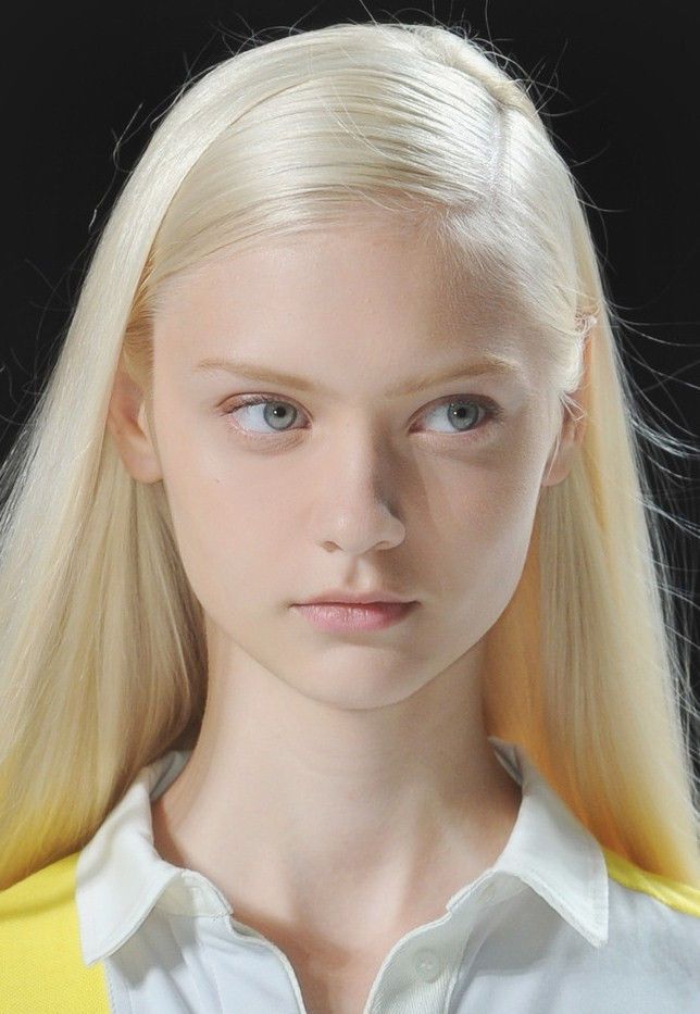 Young woman with long blonde hair and blue eyes wearing a white collar shirt