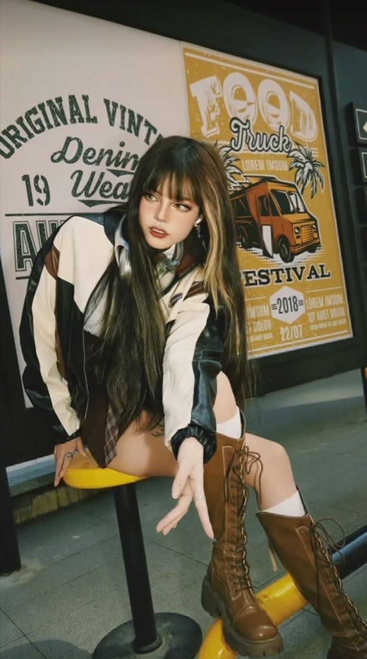 Woman in a varsity jacket and plaid skirt sitting on a yellow stool
