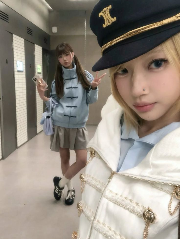 Two women posing indoors, one in a captain hat and the other with pigtails
