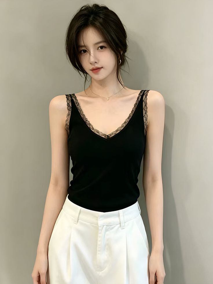 Woman with black hair wearing a black lace-trim camisole and white pants