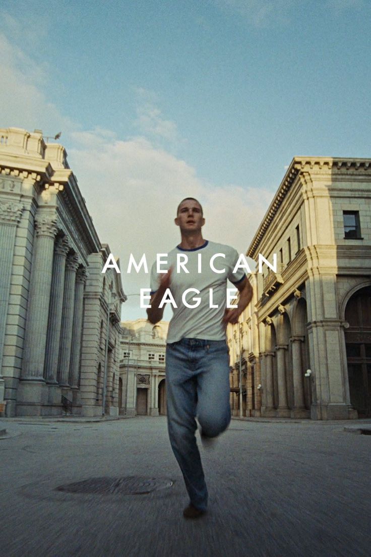 Man in a white t-shirt and blue jeans running on a city street