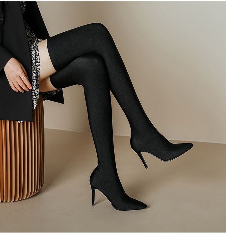 Person wearing black thigh-high boots and a blazer over a floral dress