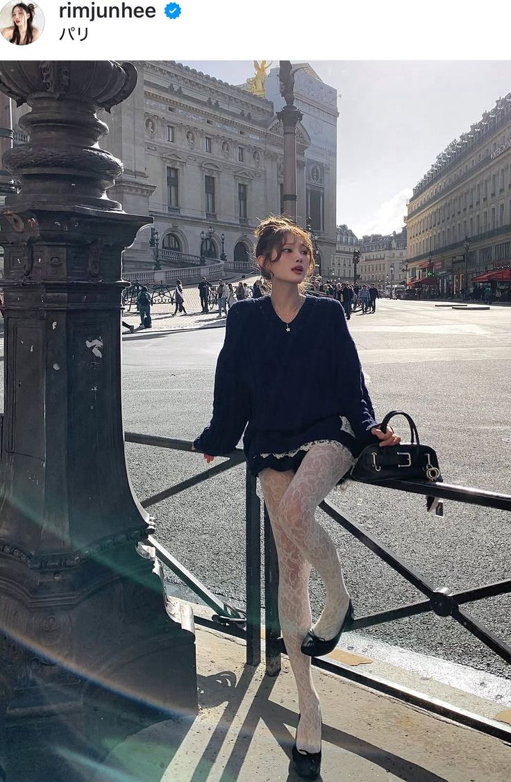 Woman in a navy sweater and white lace tights posing on a city street