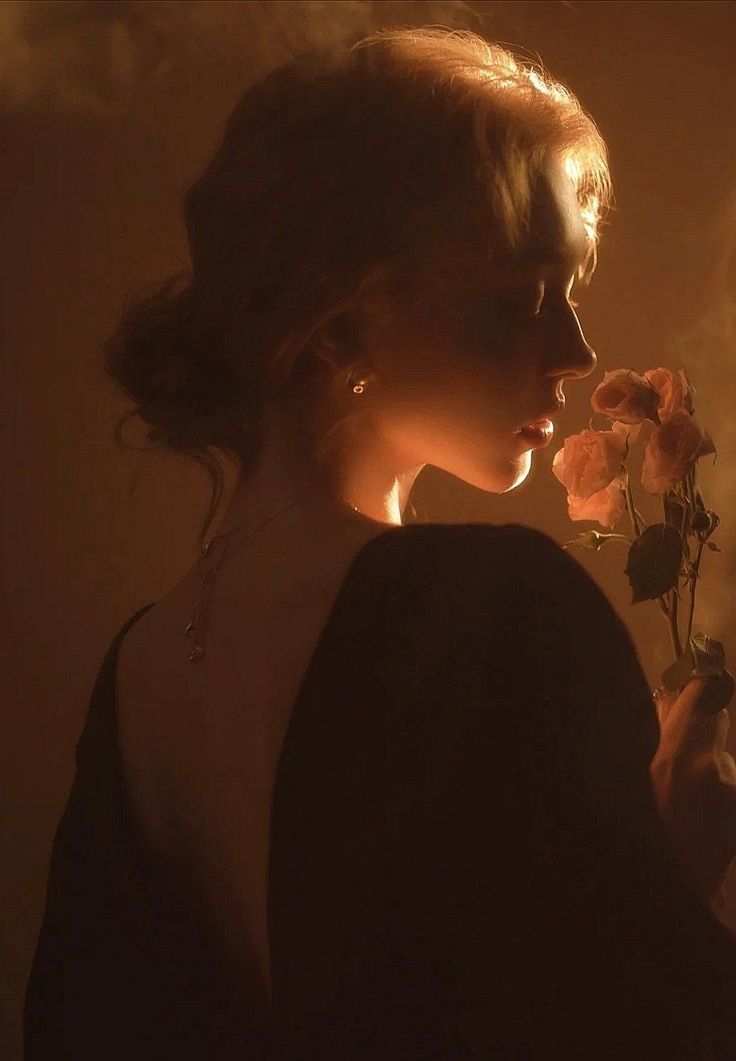 Woman in profile holding roses, illuminated by warm backlight