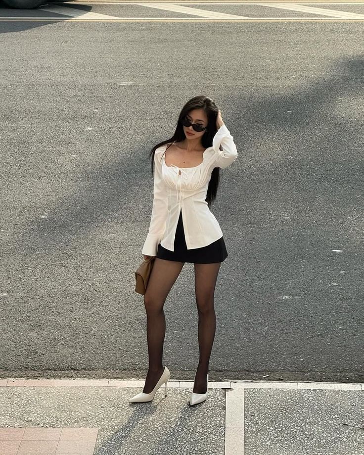 Woman in a white shirt and black skirt with sunglasses on a street