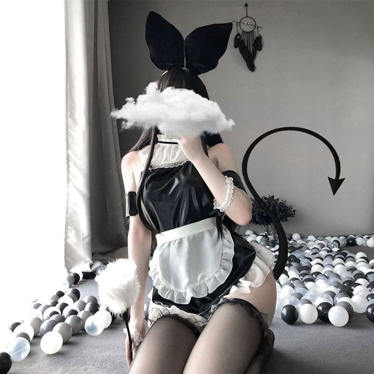 Person in a maid costume with bunny ears and a devil tail kneeling in a ball pit