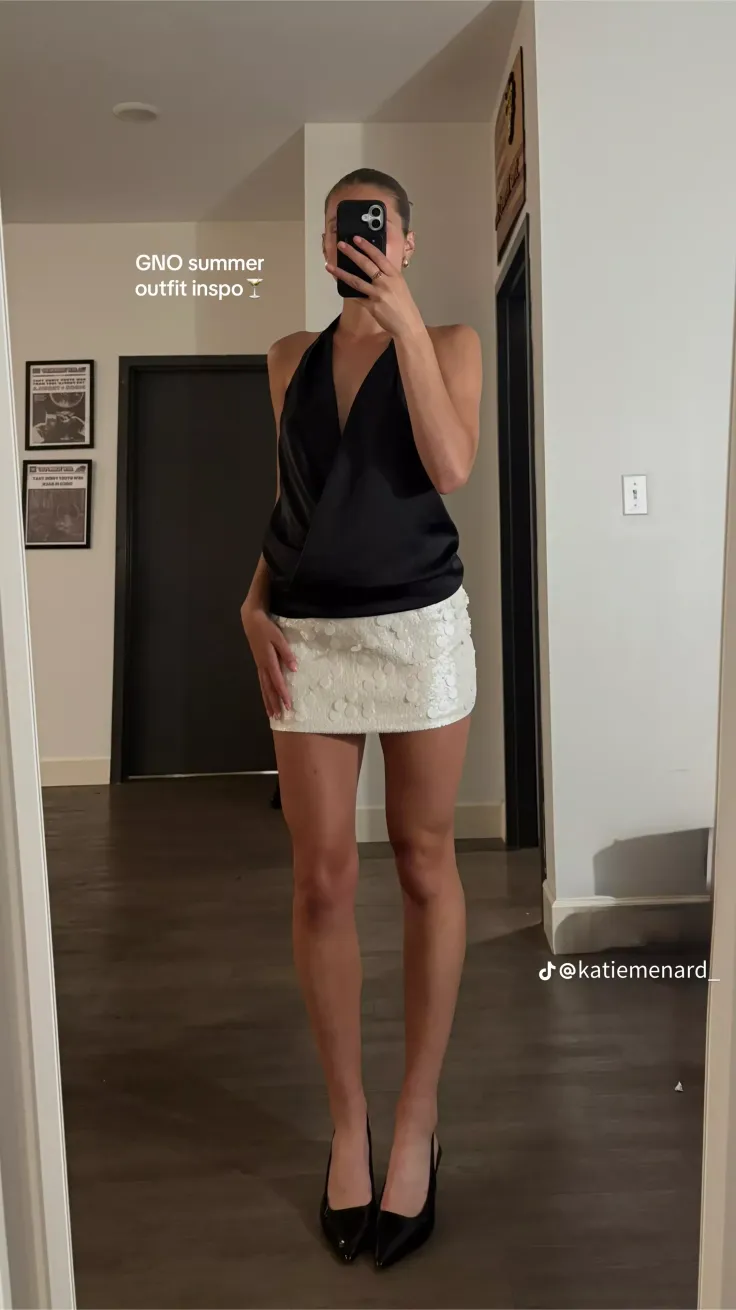 Woman in a black halter top and sequin skirt taking a mirror selfie