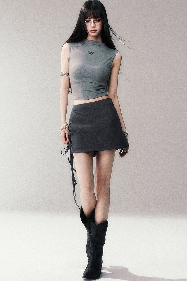 Woman with long black hair wearing a crop top, mini skirt, and cowboy boots