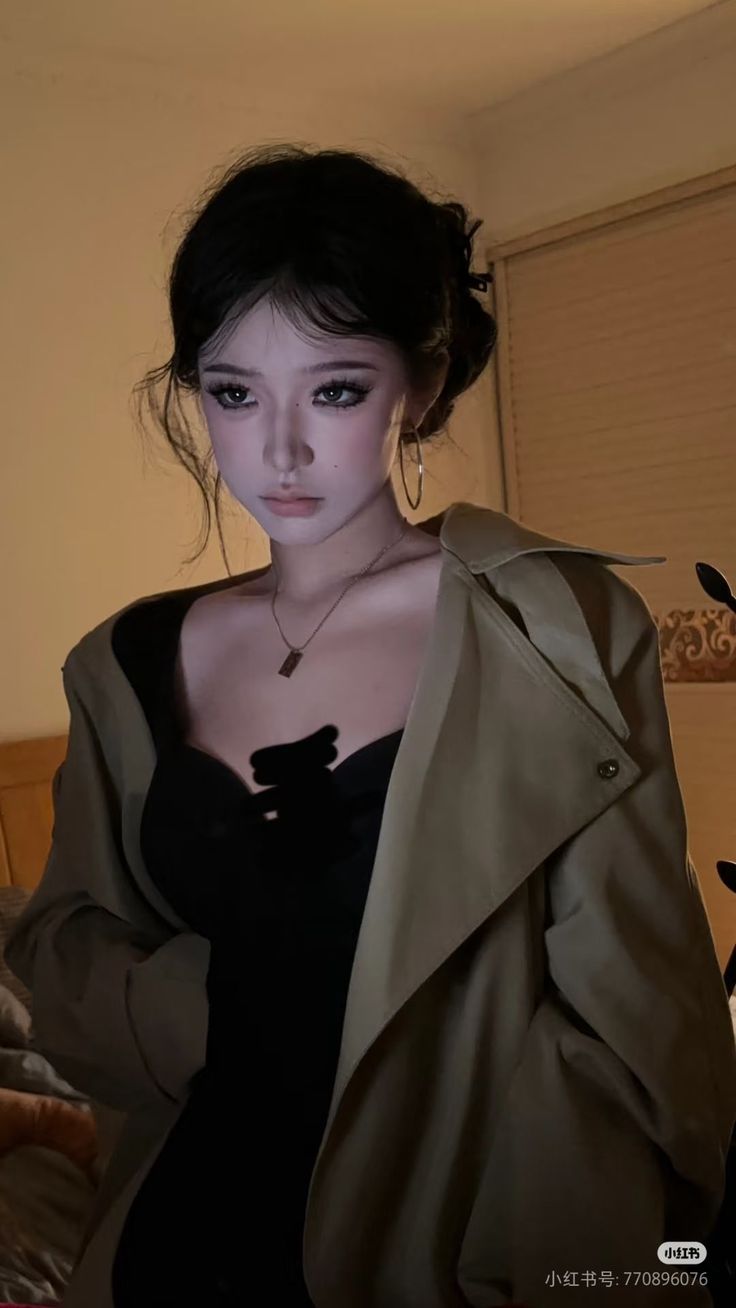 Woman with an updo and trench coat over a black top, indoors
