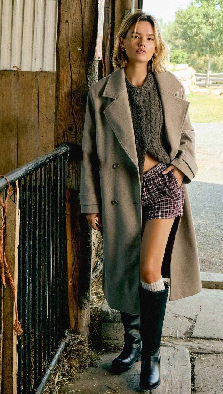 Woman in a long coat, plaid shorts, and black boots outdoors