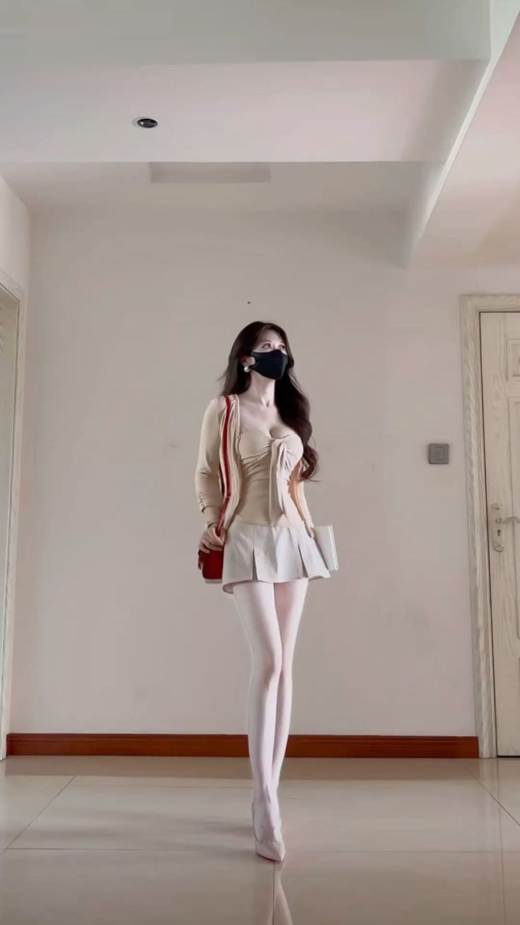 Woman in a pleated skirt and white tights posing indoors