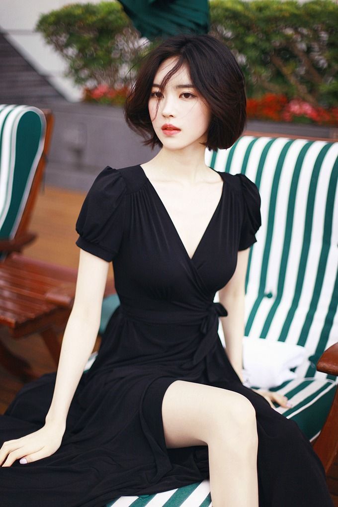 Woman with short hair in a black dress sitting outdoors