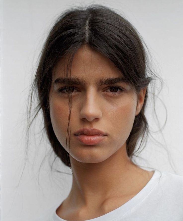 Woman with dark messy hair and natural makeup wearing a white t-shirt
