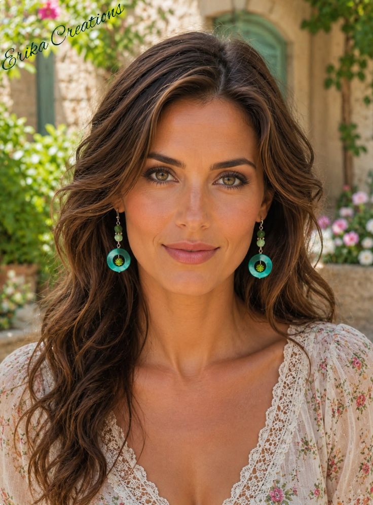 Woman with long wavy hair and green eyes wearing a floral top and earrings