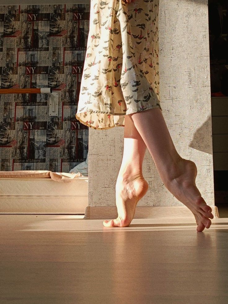 Person in a floral dress doing a ballet pose on a hardwood floor