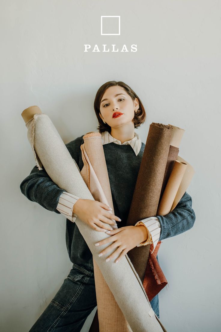 Woman with short hair and red lipstick holding rolls of fabric
