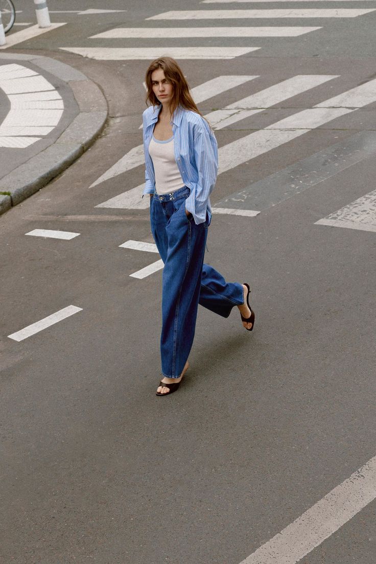 Woman in a striped shirt and loose jeans walking on a street