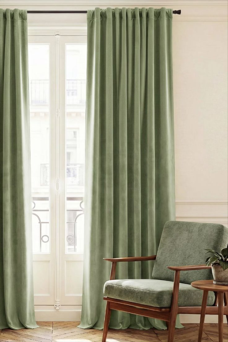 Green velvet curtains and an armchair by a window with a balcony view
