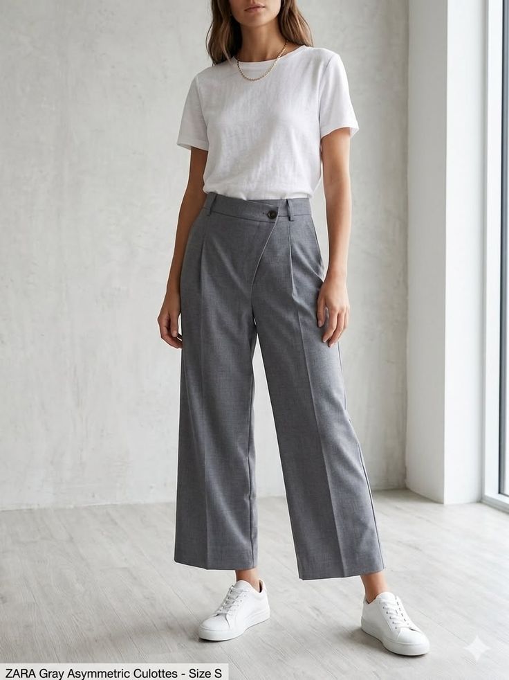 Woman in gray culottes and a white t-shirt standing indoors
