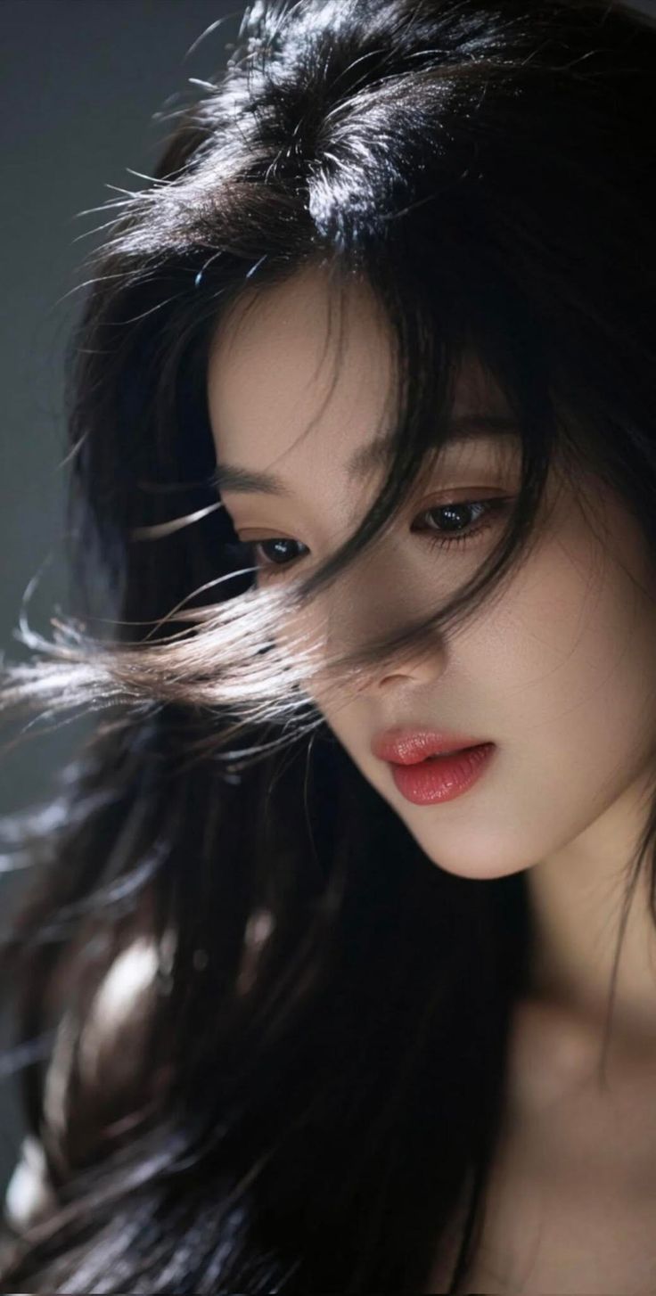 Woman with long black hair illuminated by backlight, looking down