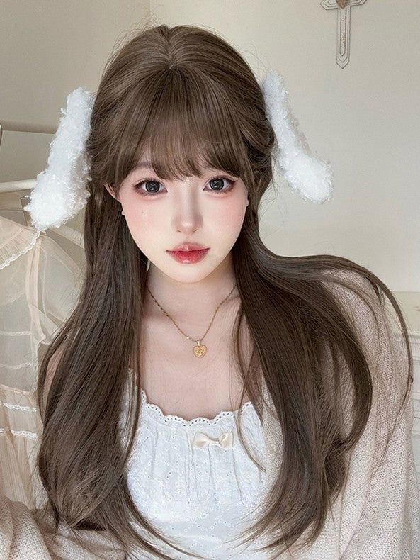 Woman with long brown hair and bunny ear accessories wearing a white top