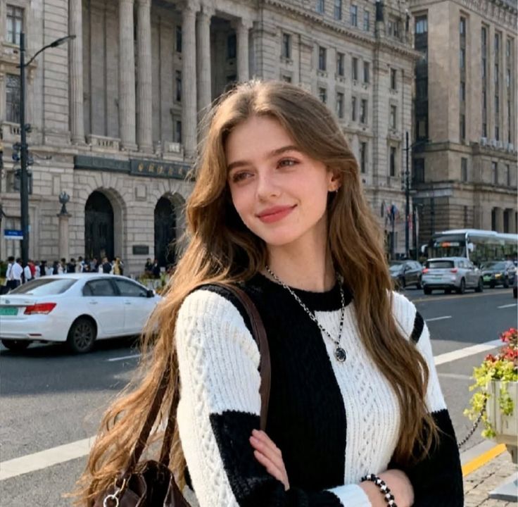 Woman with long hair in a black and white sweater on a city street