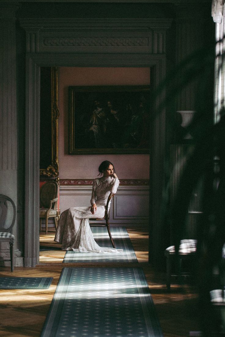 Woman in a white wedding dress sitting on a chair in a dimly lit room