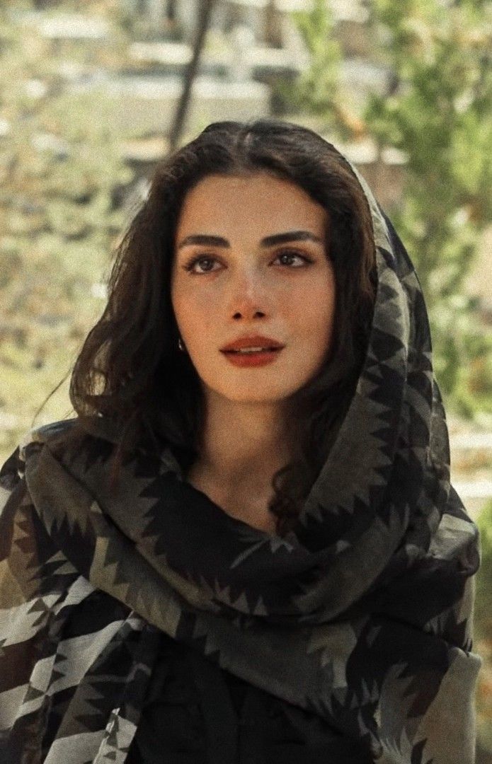 Woman with dark hair wearing a patterned headscarf outdoors