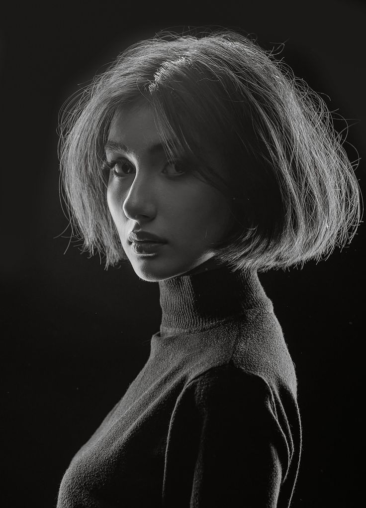 Woman with short hair in a turtleneck, dramatically lit in black and white