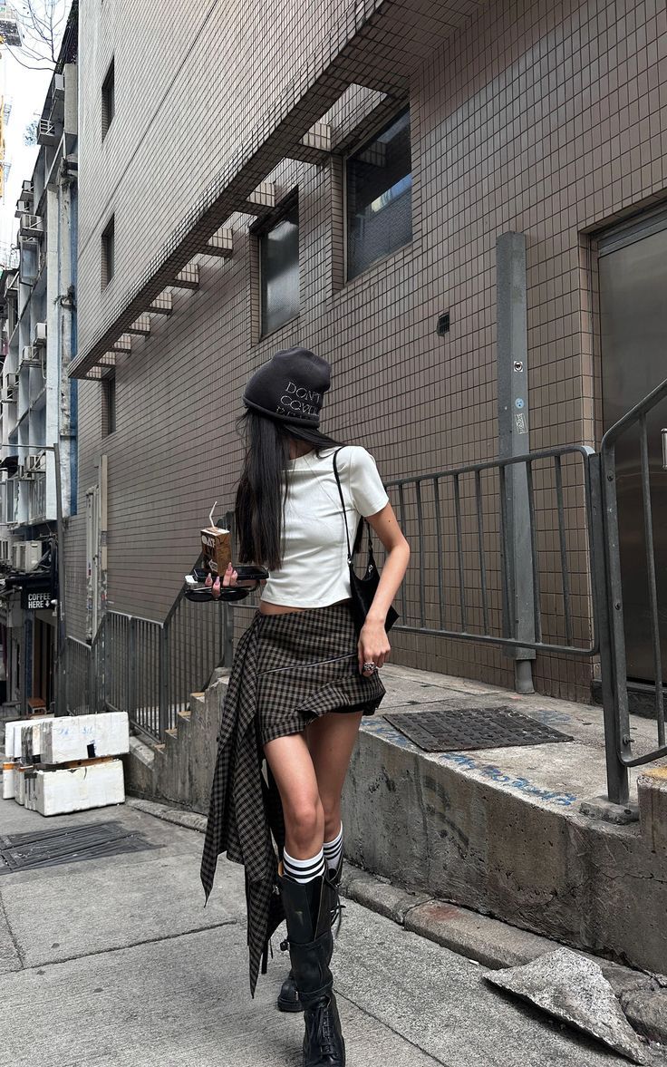 Woman in a plaid skirt and crop top walking on an urban street