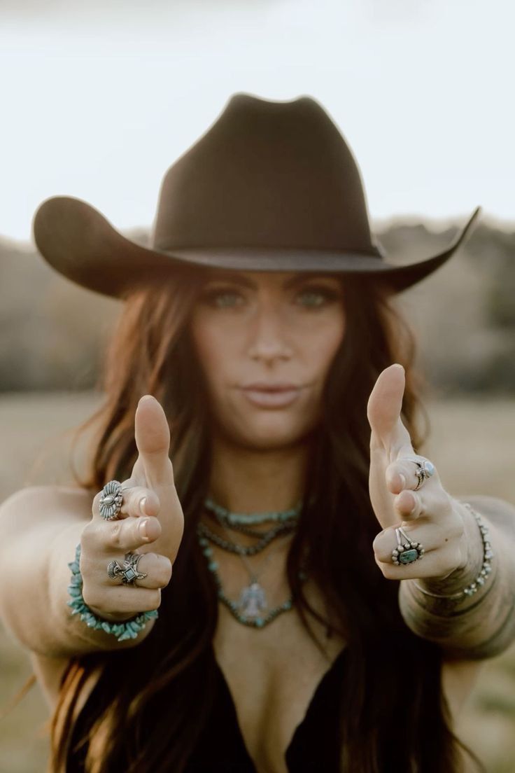Woman in a cowboy hat and turquoise jewelry making finger gun gestures