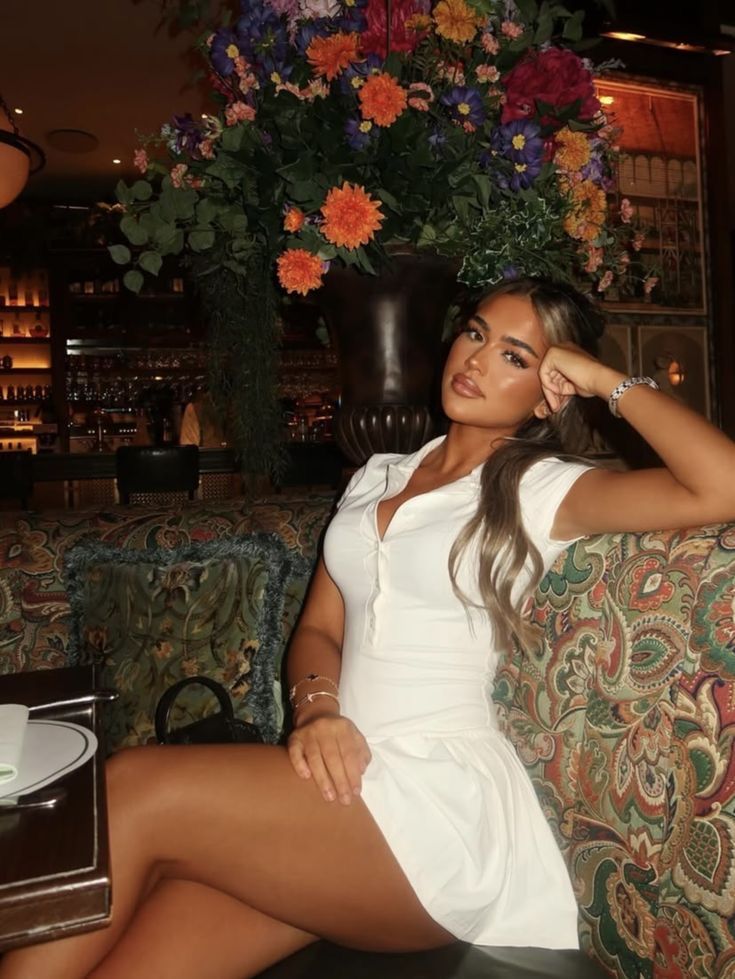Woman in a white dress sitting on a patterned couch in a restaurant