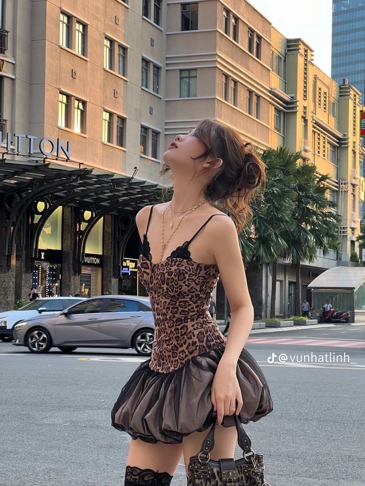 Woman in a leopard print dress and high socks on a city street at golden hour