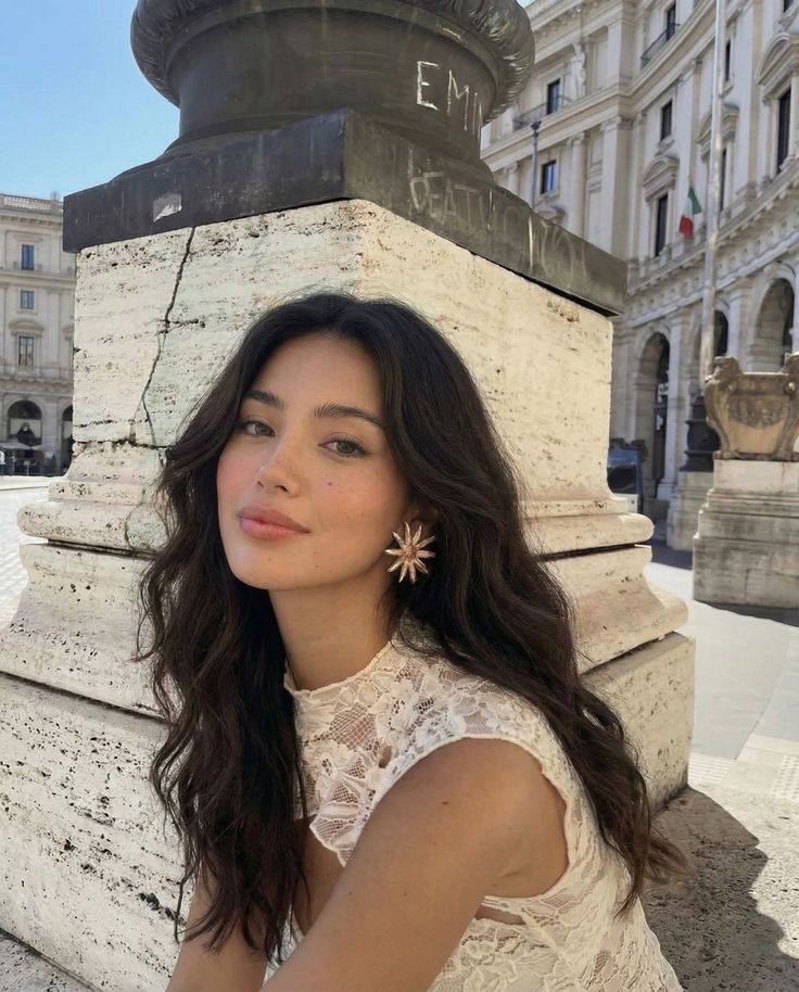 Woman with long dark hair and a lace dress outdoors in a city