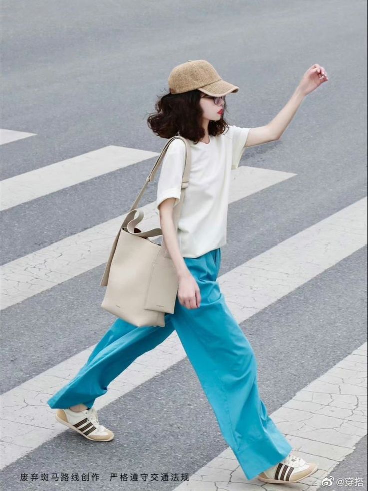 Person in a baseball cap and blue pants walking on a crosswalk