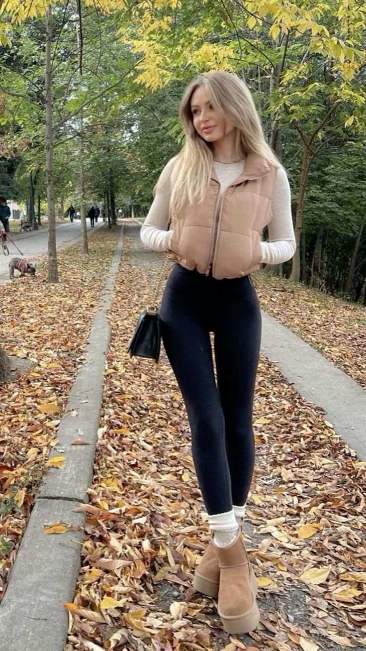 Woman with long blonde hair wearing a puffer vest and black leggings outdoors