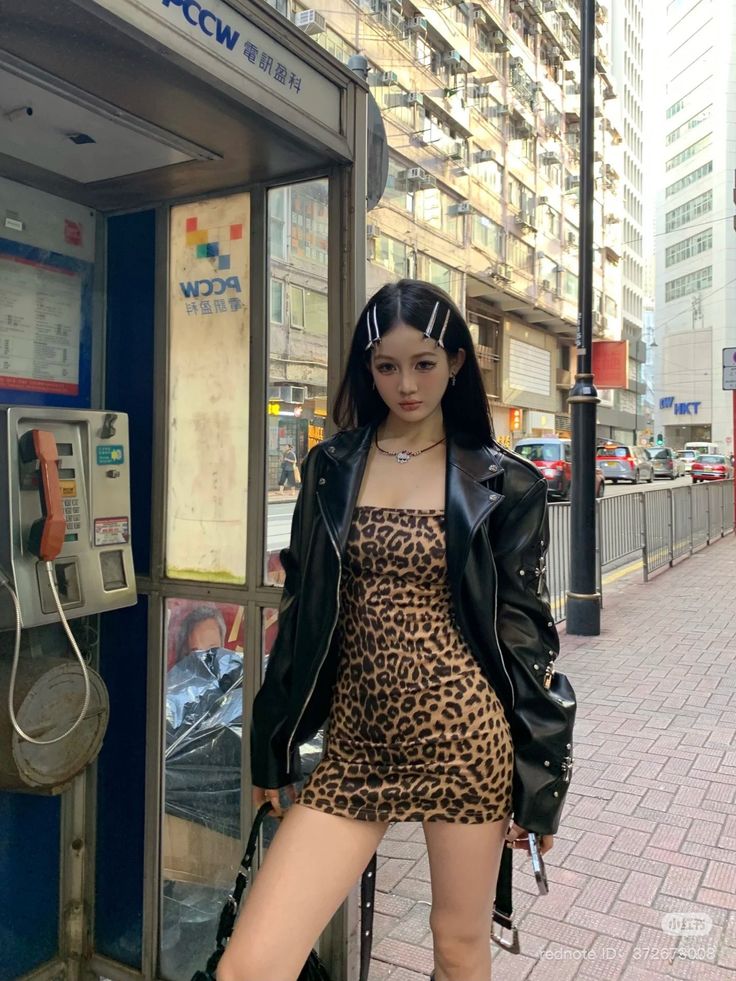 Woman in a leopard print dress and leather jacket on a city street