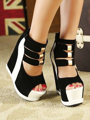 Close up of feet wearing black and white wedge heels with gold buckles