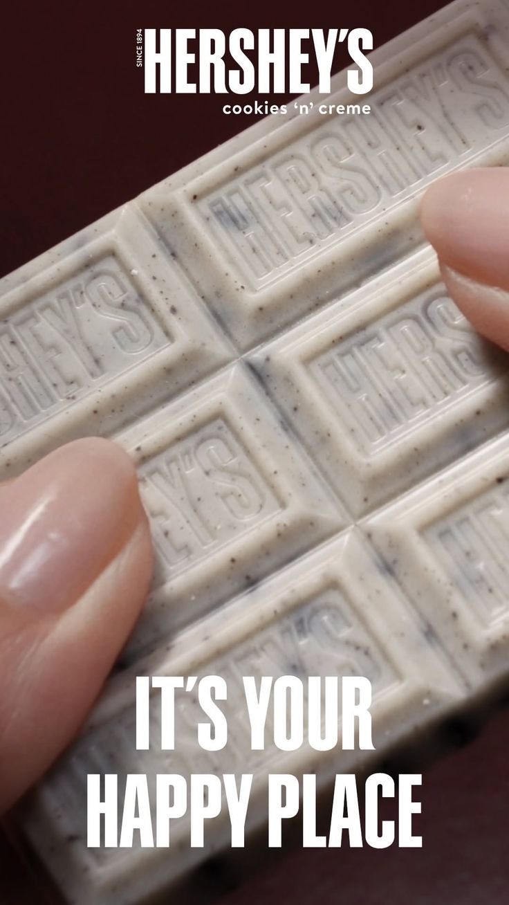 Fingers holding a Hershey's Cookies 'n' Creme chocolate bar