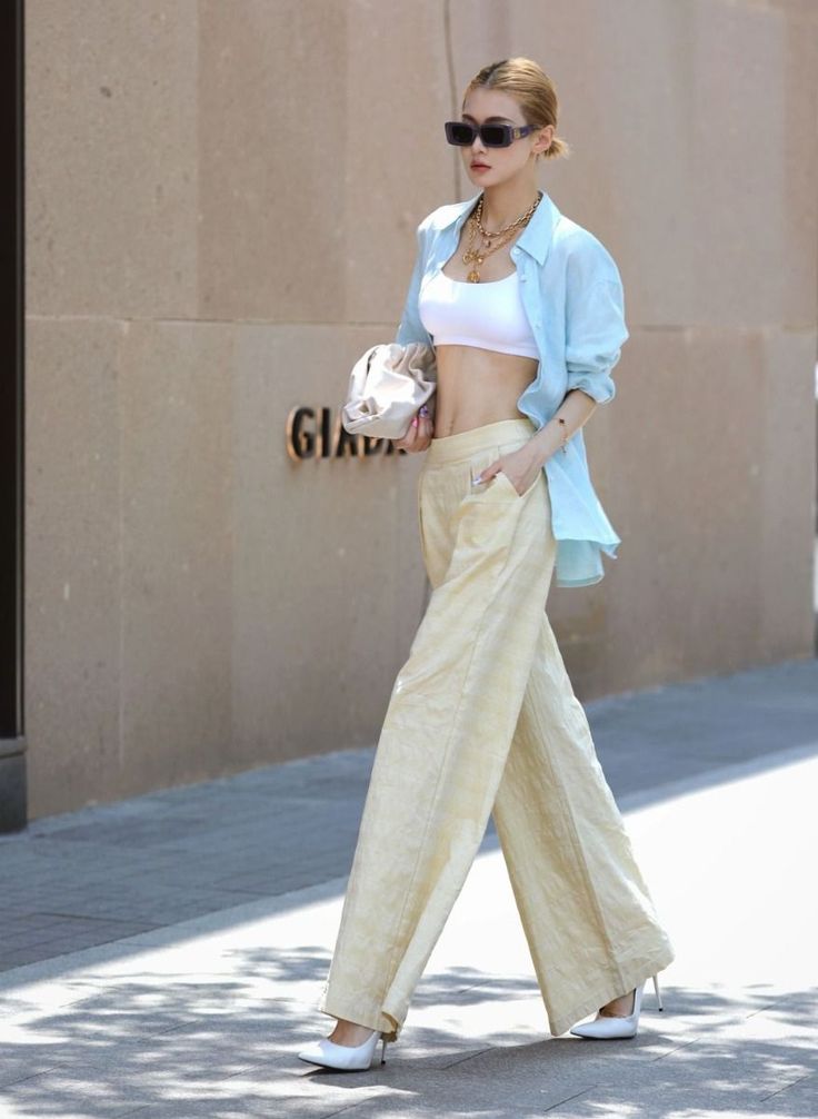 Woman in a white crop top and wide leg pants walking on a street