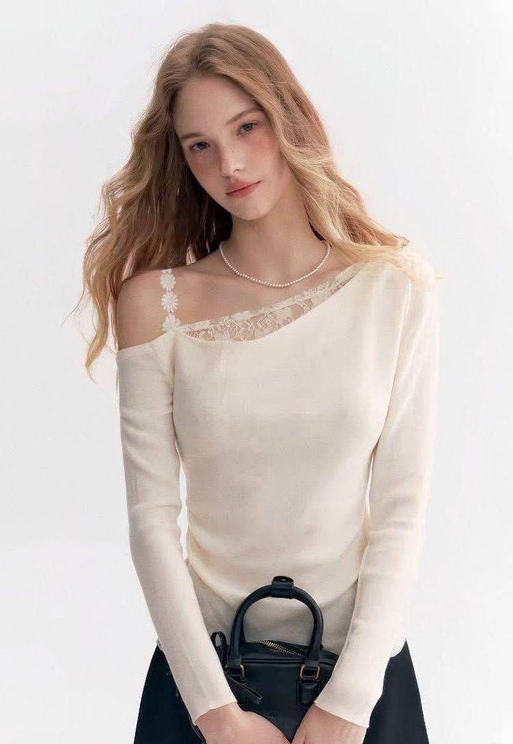 Woman with long hair wearing an off-shoulder top and pearl necklace, holding a black handbag