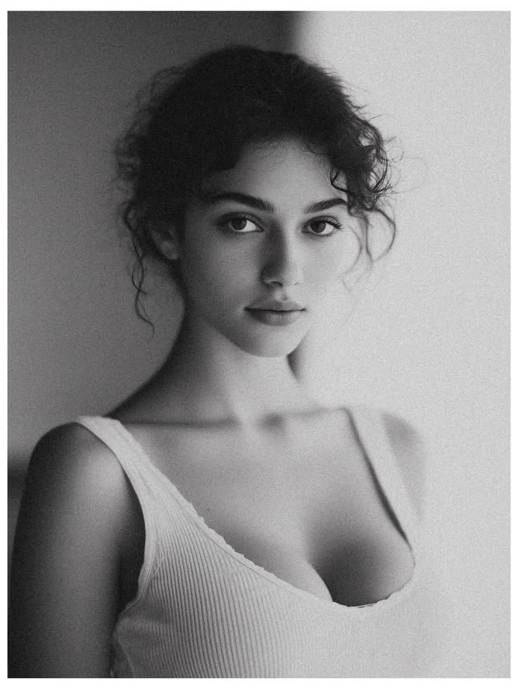 Black and white portrait of a woman with curly hair in a white tank top