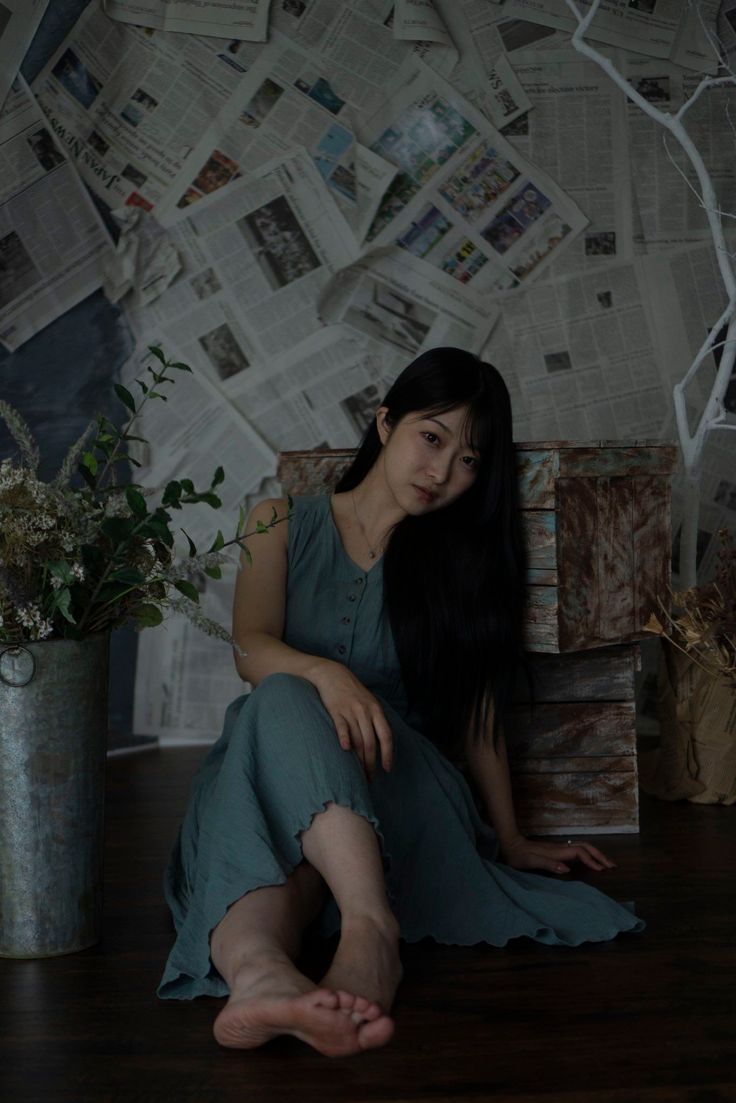 Woman with long black hair sitting on the floor in a sleeveless dress