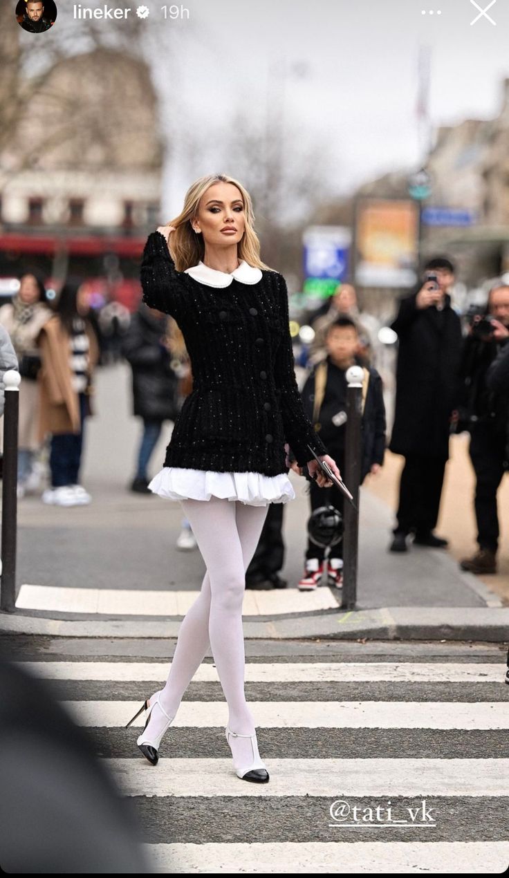 Woman with blonde hair in a black dress and white tights on a street