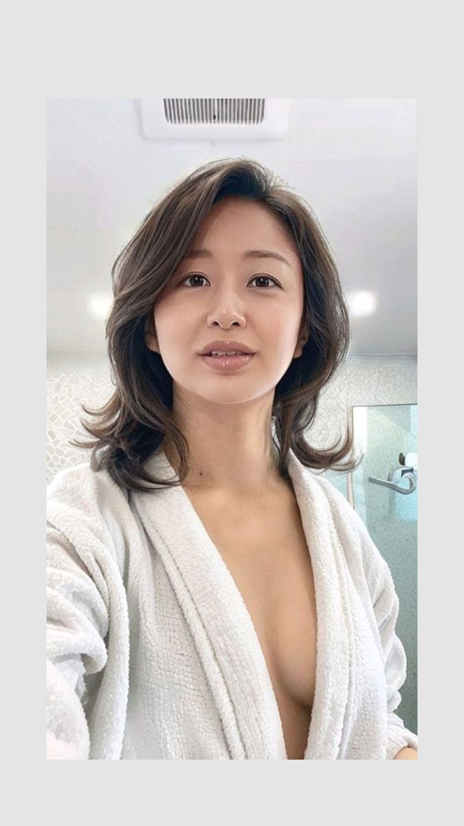 Woman in a white bathrobe with cleavage visible, in a bathroom