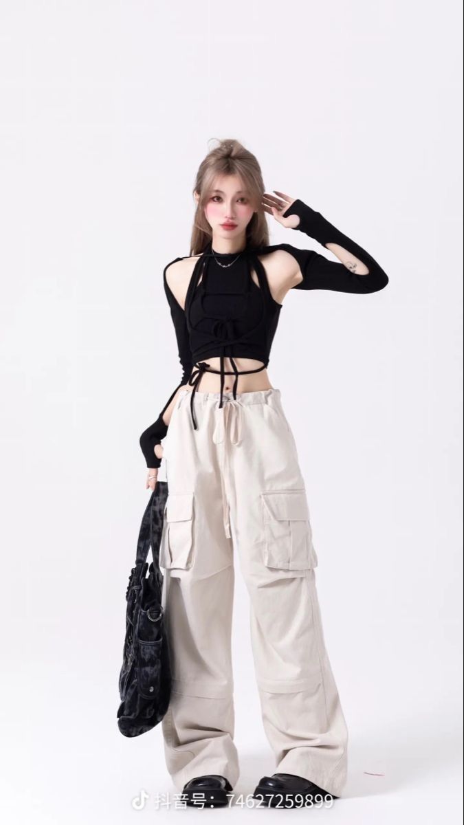 Woman in a black crop top and cargo pants posing against a white background
