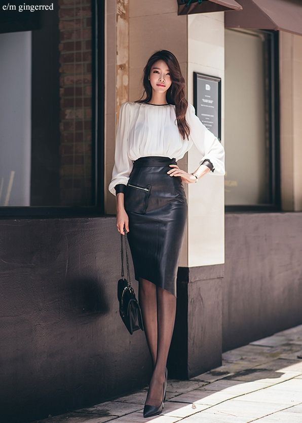 Woman in a white blouse and black leather skirt posing outdoors