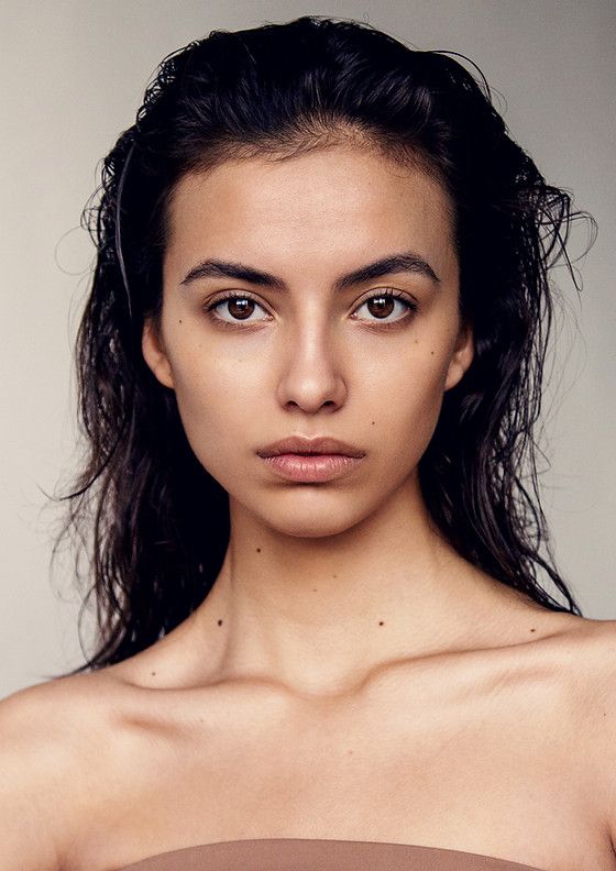 Woman with wet dark hair and bare shoulders in a studio portrait